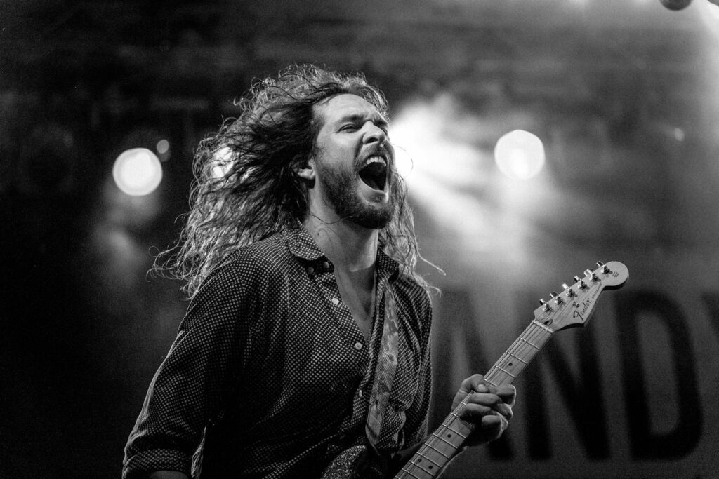 Expressive guitarist passionately performing live on stage in black and white.