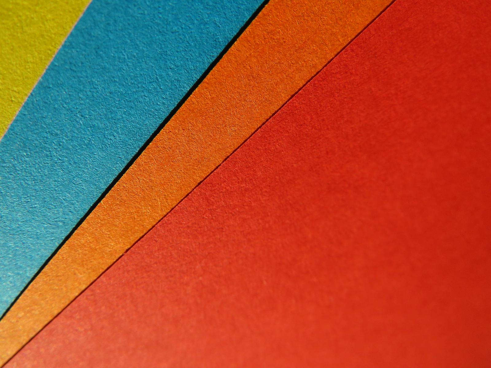 Close-up of vibrant, colorful paper sheets arranged in a geometric pattern, perfect for artistic backgrounds.