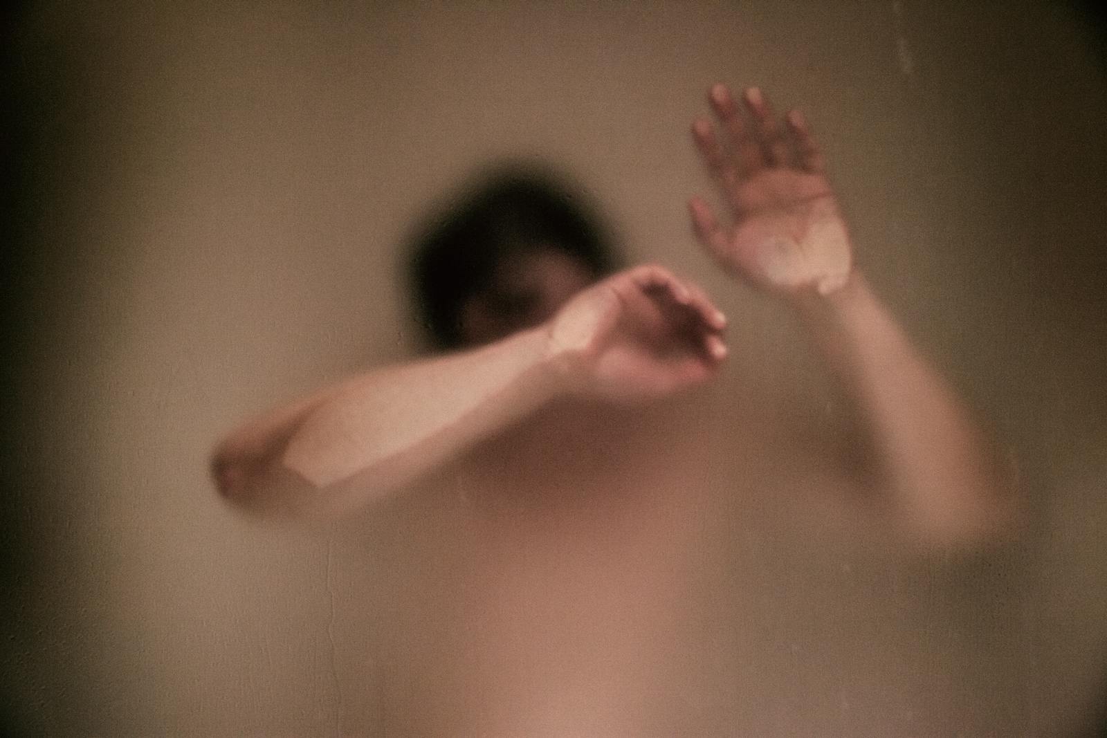 Abstract image of a person behind foggy glass, evoking themes of solitude and introspection.