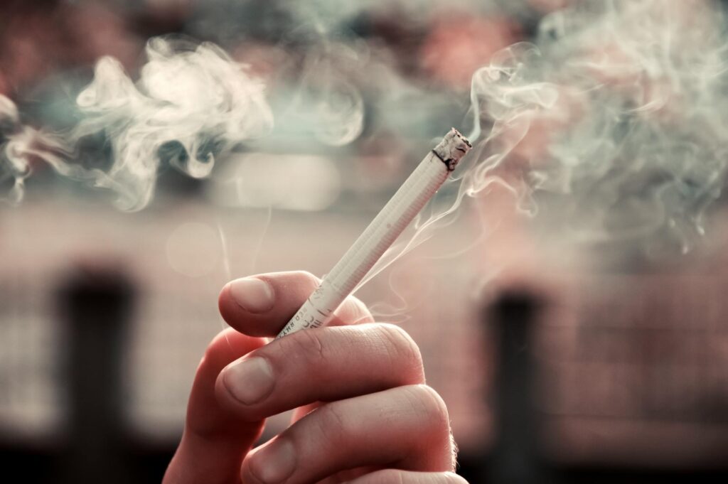 a person holding a cigarette stick